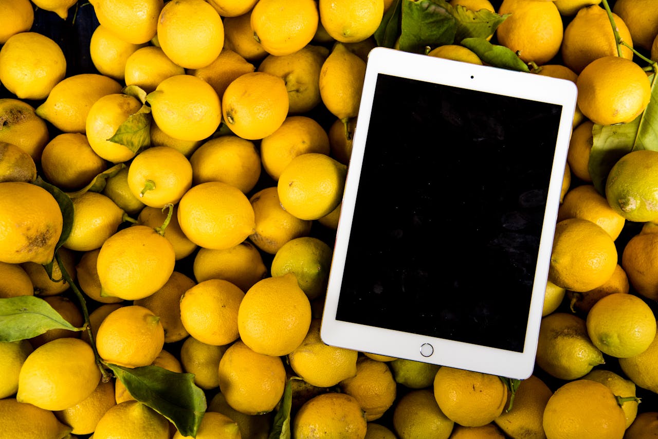 A bright, fresh collection of lemons with a blank tablet screen for copyspace.